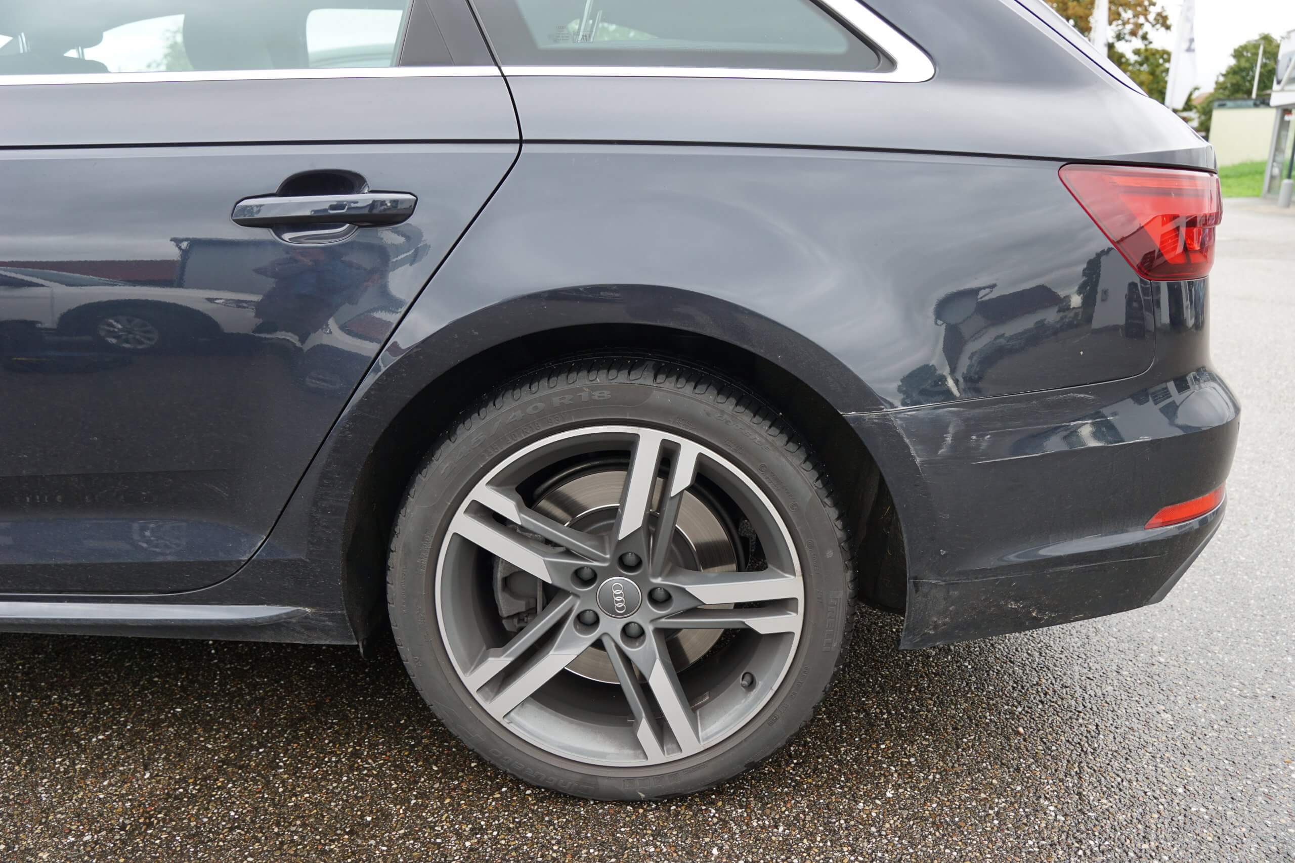 Nahaufnahme des Hinterrads und Seitenteils eines dunkelgrauen Autos auf nasser Straße, gut geeignet zur Dokumentation für ein Unfallgutachten