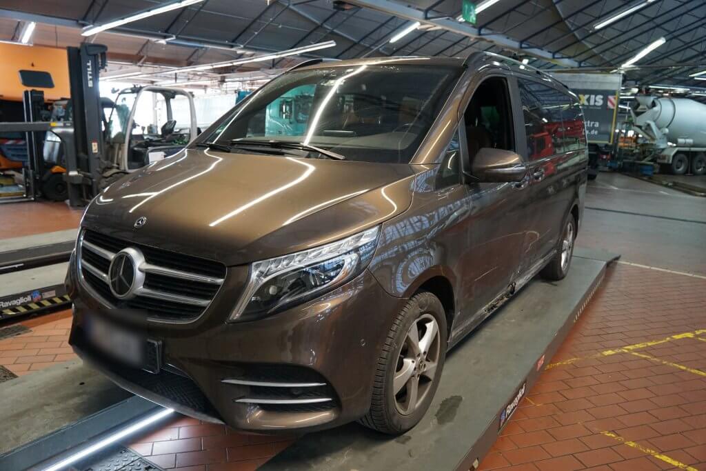 Ein brauner Mercedes-Benz Transporter steht in einer Autowerkstatt auf einer Hebebühne