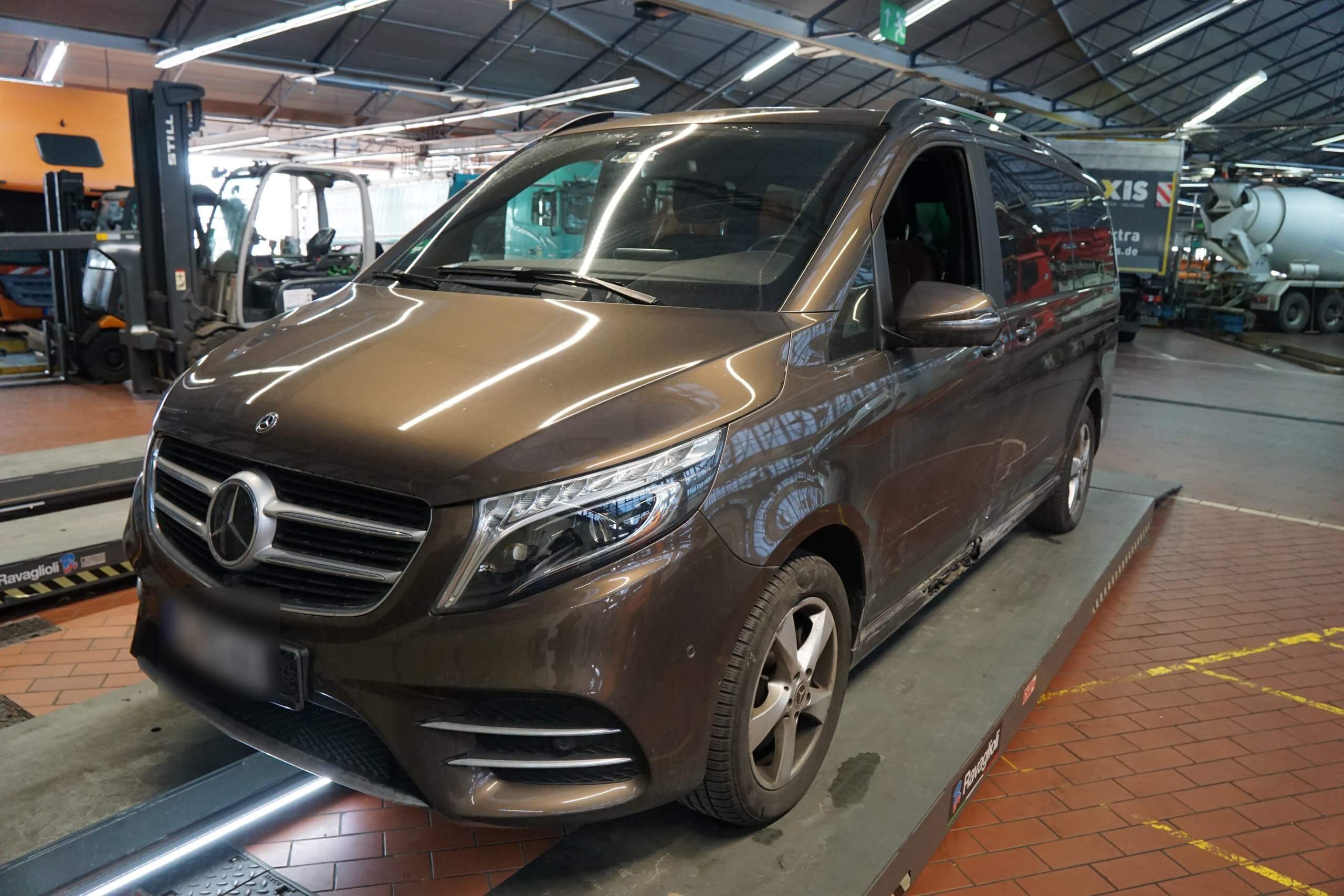 Ein brauner Mercedes-Benz Transporter steht in einer Autowerkstatt auf einer Hebebühne